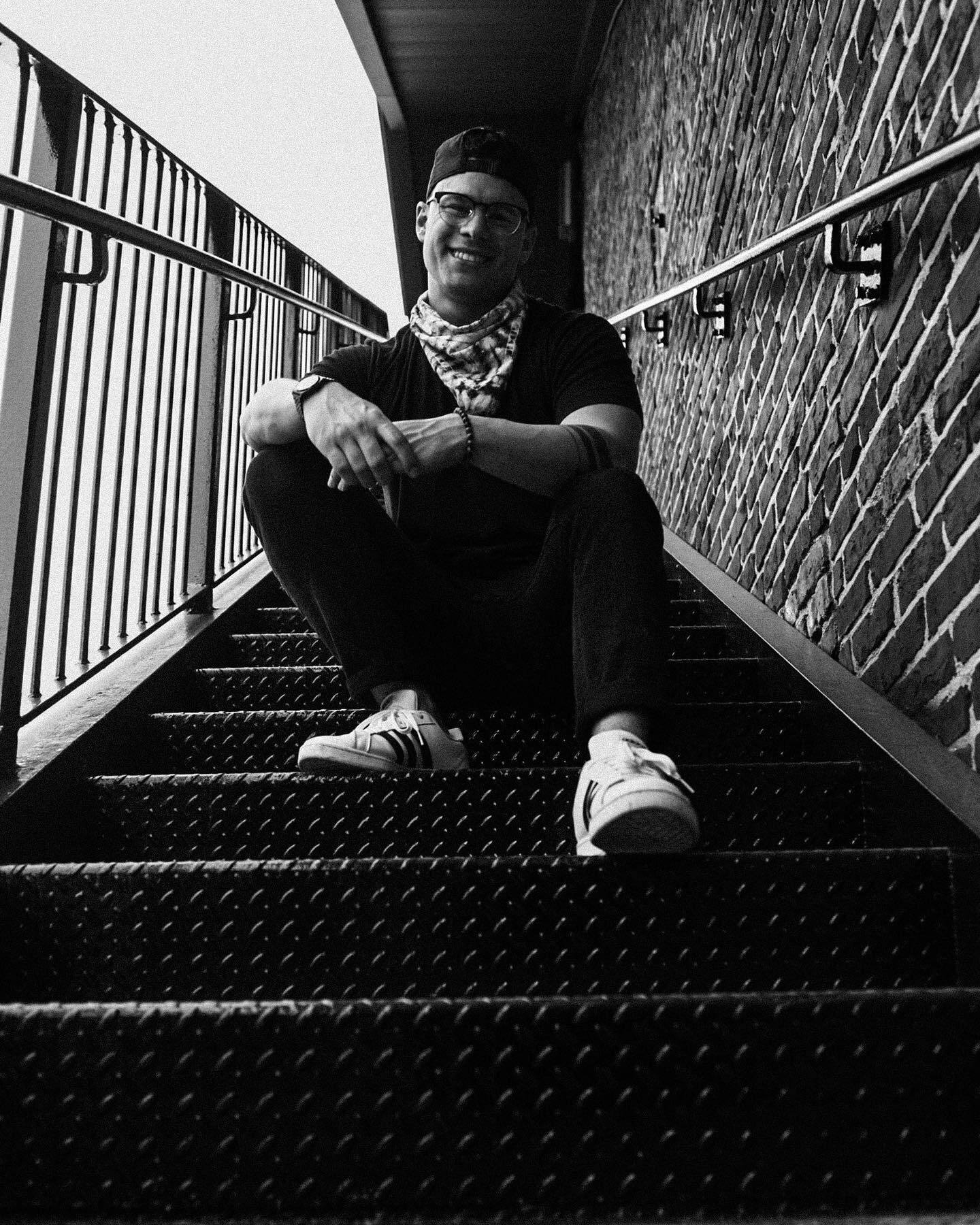 Sitting on an iron fire escape, looking down into the lens