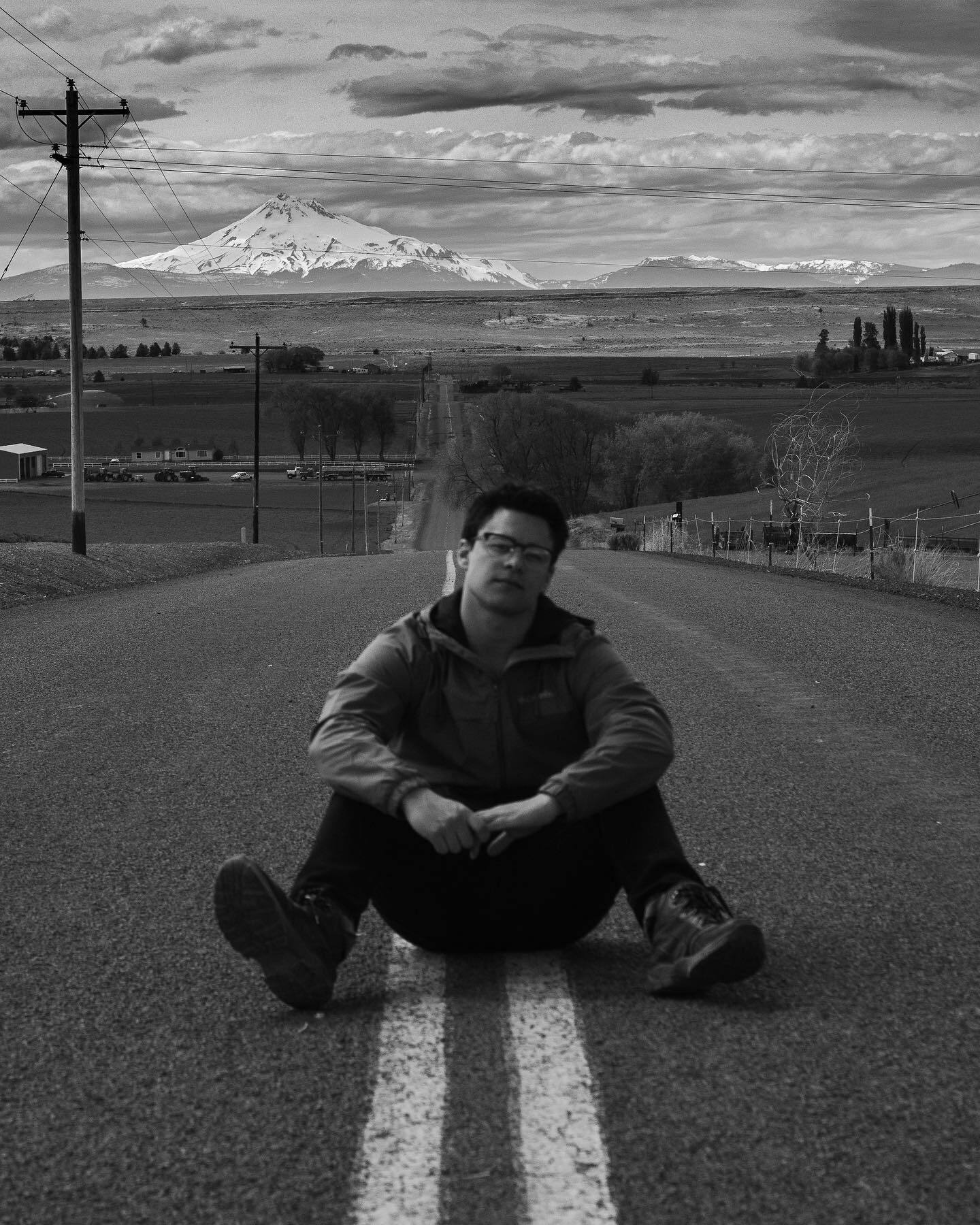 Sitting on the centre line of an empty road with a snow-capped mountain behind