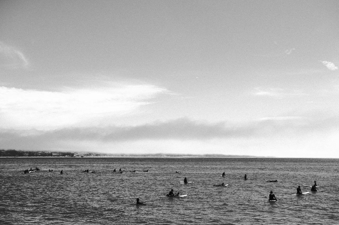 Surfers waiting in flat grey water, black and white
