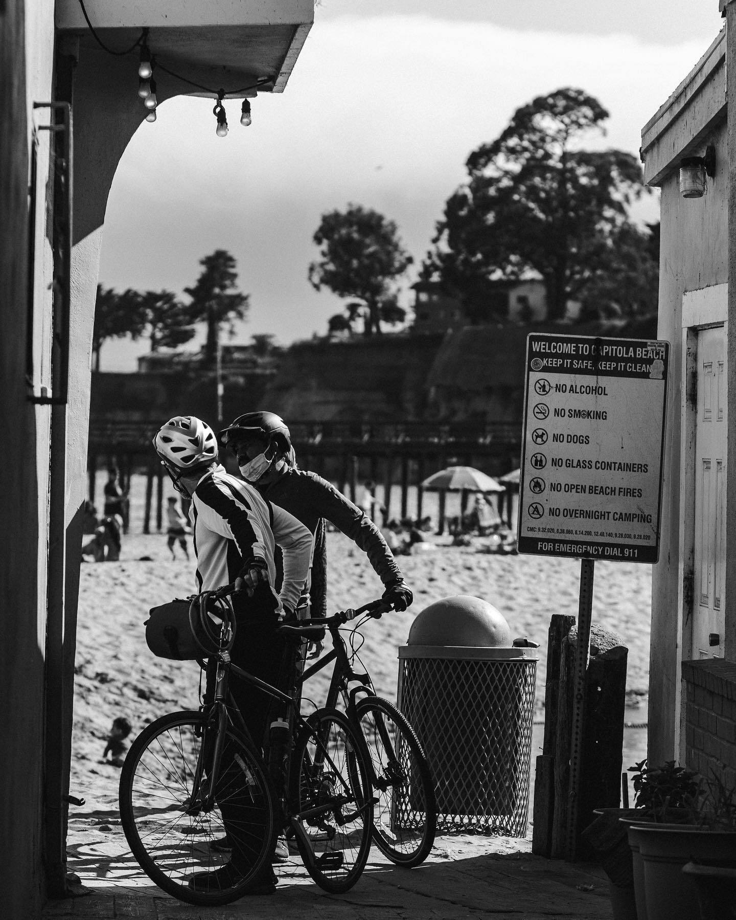 A cyclist in a helmet reads a beach notice board