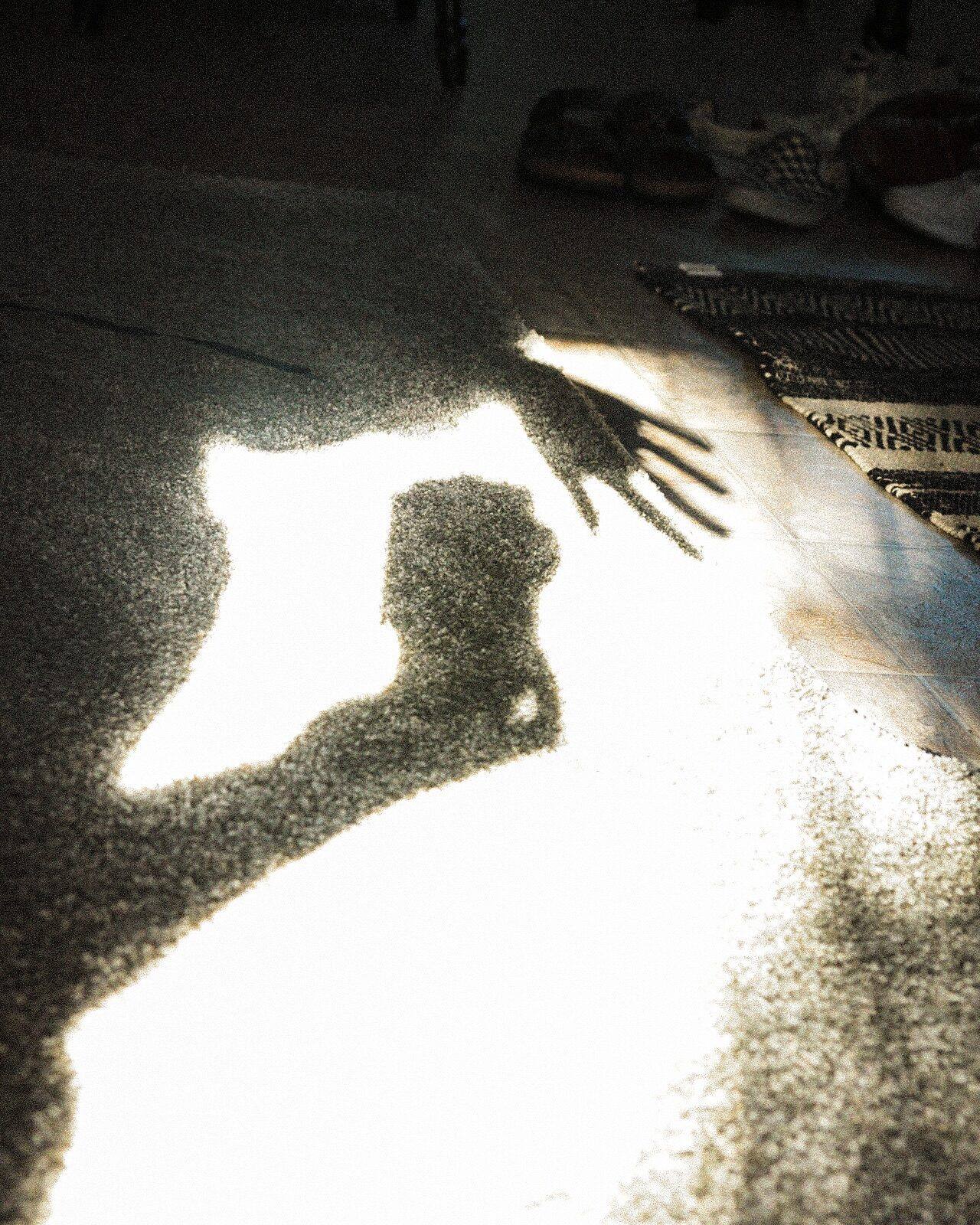 The shadow of a hand on a rug in low afternoon sun