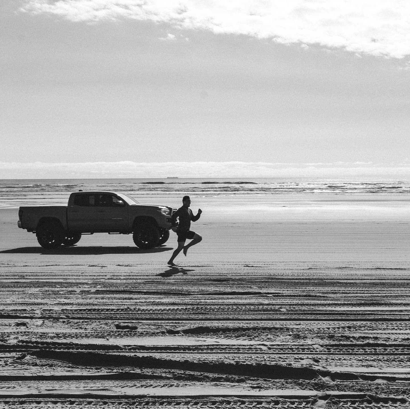 A pickup and a runner on wide wet sand