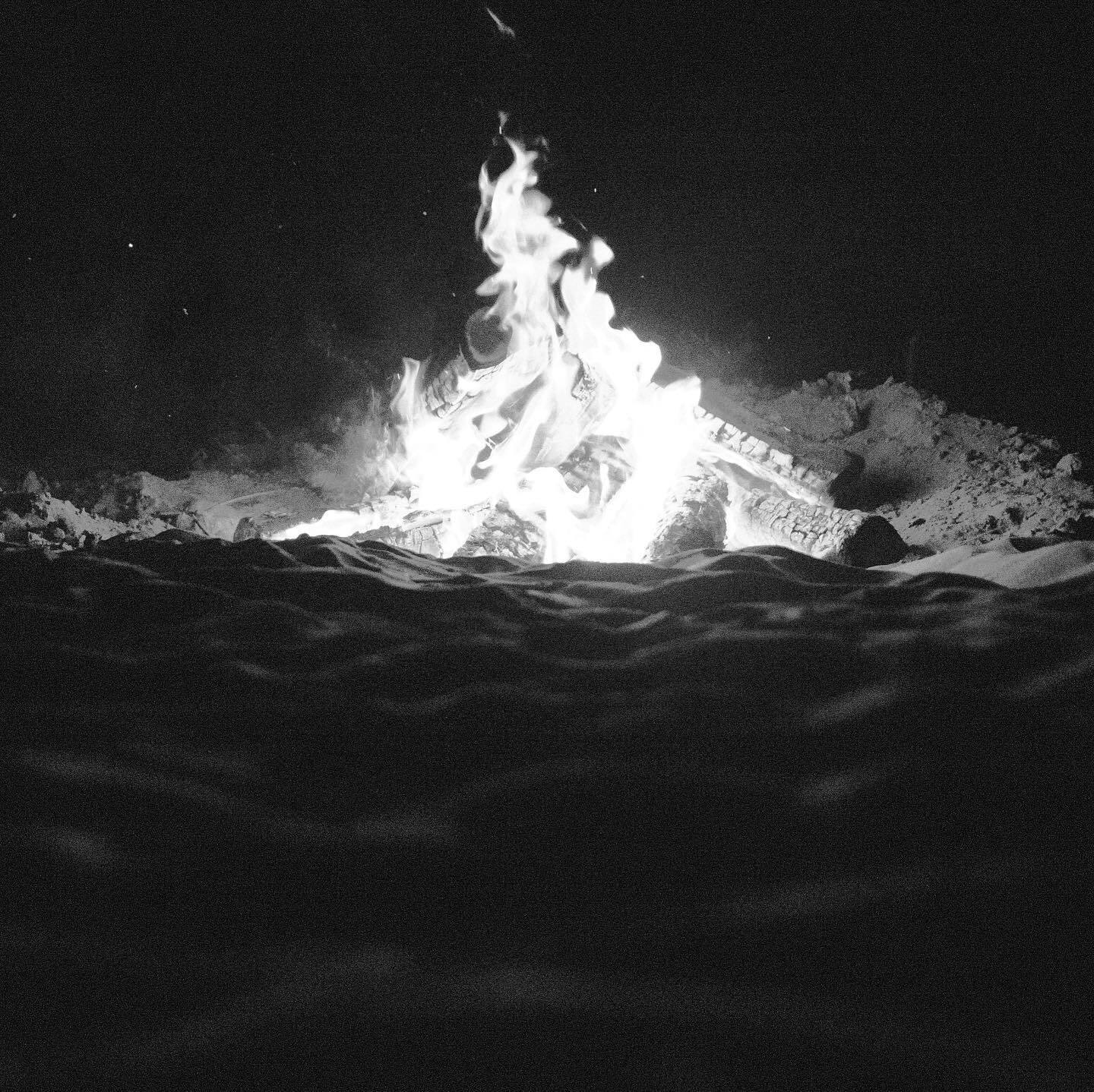 A bonfire burning on the sand at night